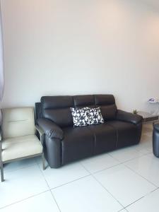 um sofá de couro preto e uma cadeira num quarto em Seaview Condo 10pax #10minQueensbay #15minSpice em Bayan Lepas