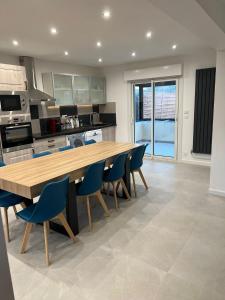 a kitchen with a wooden table and blue chairs at Maison Rénovée Aux Portes Du Circuit Des 24h in Mulsanne