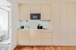 a kitchen with white cabinets and a sink at Dans l'ancien Grand Hôtel charmant studio in Houlgate