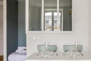 einen Tisch mit Weingläsern und einem Spiegel in der Unterkunft Comfortable studio in the Grand Hôtel of Houlgate - Welkeys in Houlgate
