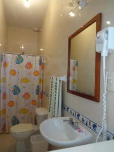 een badkamer met een wastafel, een toilet en een spiegel bij Hotel Figueroa in San Andrés Tuxtla