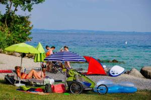 grupa ludzi siedzących na plaży z parasolami w obiekcie Fornella Camping & Wellness family resort w mieście San Felice del Benaco