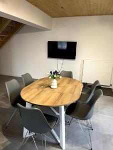 a wooden table with chairs and a television on a wall at Nowy apartament dla 6 osob in Krynica Zdrój