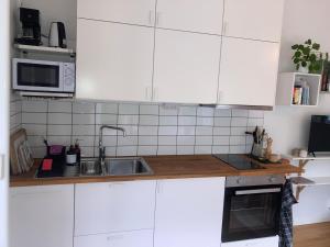 a kitchen with white cabinets and a sink at Tiny grey house with loft, 15 min from city center in Gothenburg