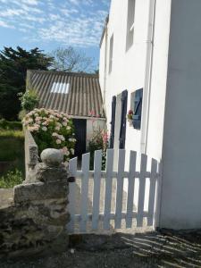 une maison blanche avec une clôture blanche et des fleurs dans l'établissement Maison de vacances 5-7 personnes, à Saint-Pierre-Quiberon