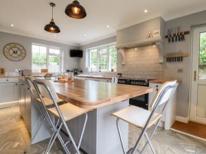 a kitchen with a wooden counter top and chairs at Church Cottage in Diss