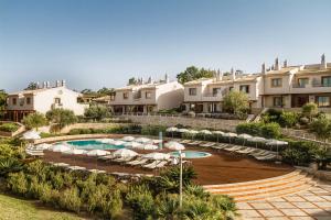 a resort with a pool and chairs and buildings at Grande Real Santa Eulalia Resort & Hotel Spa in Albufeira