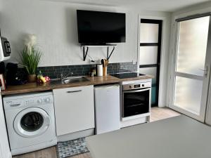 uma cozinha com uma máquina de lavar roupa e uma televisão na parede em LE GAUGUIN, T2 Cosy, 2-4 Pers, à 300m des plages em Clohars-Carnoët