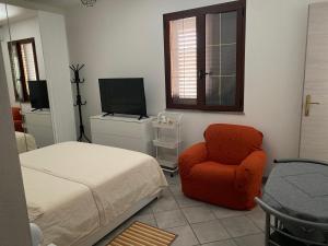 una camera con letto, sedia e televisore di La casa di Giogio a Monserrato