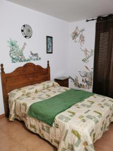 a bedroom with a bed with a green blanket at Posada la Maza in Arnuero