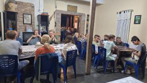 een groep mensen die rond een tafel in een restaurant zitten bij Smiley's Homestay in Berastagi