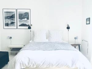 sypialnia z białym łóżkiem z dwoma obrazami na ścianie w obiekcie The Art Room Apartment w mieście Cardigan