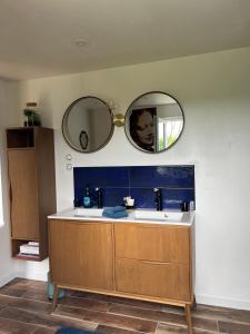 ein Badezimmer mit einem Waschbecken und zwei Spiegeln an der Wand in der Unterkunft Wanatan Chambre d'hôtes in Penmarcʼh