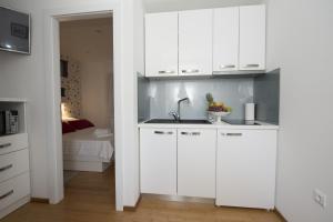 a kitchen with white cabinets and a sink and a bed at Apartments Annya in Split