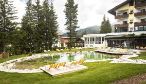 un complejo con una piscina con sillas y un edificio en Bergresort Seefeld en Seefeld in Tirol