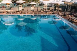 a large blue swimming pool with chairs and umbrellas at Real Bellavista Hotel & Spa in Albufeira