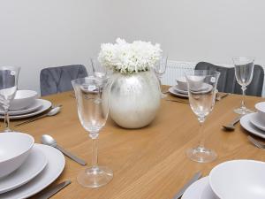 a wooden table with glasses and a vase with white flowers at City Centre 3 BDR Townhouse by Belfast City Breaks in Belfast