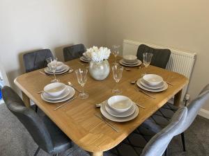 a wooden table with chairs and plates and a vase of flowers at City Centre 3 BDR Townhouse by Belfast City Breaks in Belfast