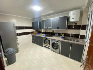 een kleine keuken met een wastafel en een wasmachine bij Appartement 3 chambres familiale in Nador