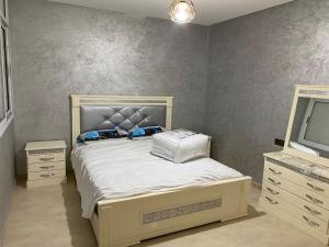 een slaapkamer met een bed, een dressoir en een tv bij Appartement 3 chambres familiale in Nador