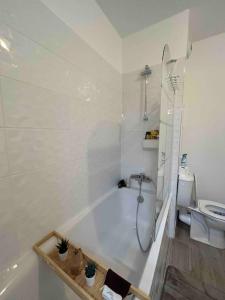 ein weißes Bad mit einer Badewanne und einem WC in der Unterkunft Chic & moderne appartement - proximité métro in Asnières-sur-Seine