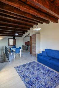 a living room with a blue couch and a kitchen at Agriturismo Case Rapputi in Lascari