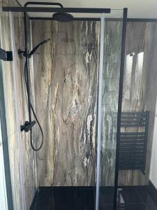 a shower in a bathroom with a stone wall at Cherry Cottage in West Mersea
