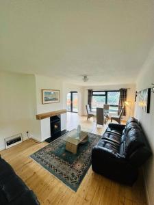 a living room with a black leather couch and a fireplace at Cherry Cottage in West Mersea