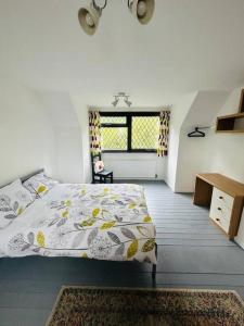 a bedroom with a bed and a desk and a window at Cherry Cottage in West Mersea