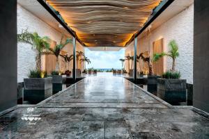 Secrets Moxché Playa del Carmen - Adults Only - All Inclusive في بلايا ديل كارمن: ممر طويل مع أشجار النخيل في مبنى