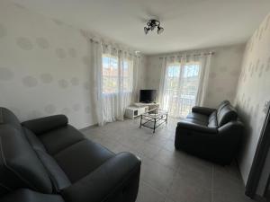 uma sala de estar com dois sofás de couro e uma televisão em Appartement lumineux em La Bâtie-Neuve