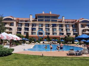 a hotel with a pool in front of a building at SUN AND FLOWERS APARTMENTS in front of the sea in Topola