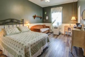 a bedroom with a bed and a couch and a window at Auberge Presbytere Mont Lac-Vert in Hébertville