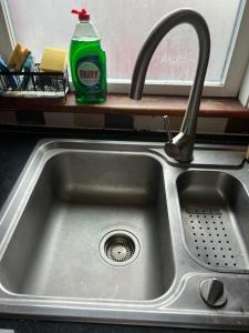 a kitchen sink with a faucet and a bottle of soda at Spacious and Sunny double Room for comfortable nap in Harrow on the Hill