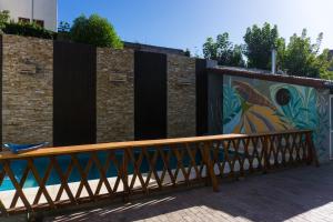 un banco de madera frente a una pared con un mural en Bitelyus Hostel Club en Mar del Plata