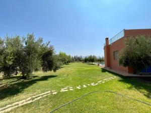 un campo de césped junto a un edificio con árboles en Villa de l'ATLAS, en Marrakech