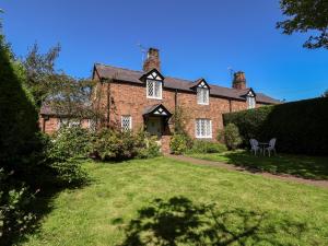 ein altes Backsteinhaus mit Rasen davor in der Unterkunft Jasmine Cottage in Chester