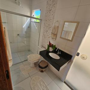 a bathroom with a sink and a toilet and a shower at Vila Axé Flat 01 Riviera in Prado