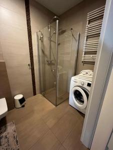 La salle de bains est pourvue d'un lave-linge et d'une douche. dans l'établissement APT Nadmorskie - Solna, à Kołobrzeg