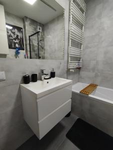 ein Badezimmer mit einem weißen Waschbecken und einer Badewanne in der Unterkunft Przytulne mieszkanie przy Kanale Żerańskim in Warschau