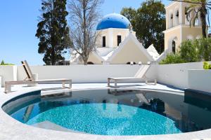 a swimming pool in front of a building with a church at Naos Suites in Vóthon