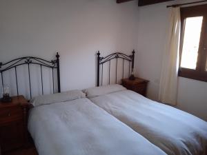 a bedroom with a bed with white sheets and a window at Casa Ben Abora in Las Rosas