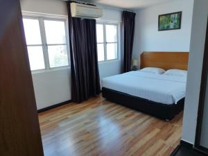 ein Schlafzimmer mit einem Bett und zwei Fenstern in der Unterkunft Marine Bay Hotel in Sandakan