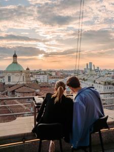a man and a woman sitting on a ledge looking at the city at The Square Milano Duomo in Milan