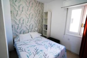 a bedroom with a bed with a blue and white blanket at Luminoso ático con vistas al mar in Almería