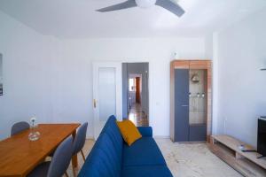 a living room with a blue couch and a table at Luminoso ático con vistas al mar in Almería