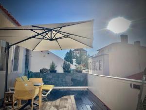 um pátio com uma mesa, cadeiras e um guarda-sol em Cristalia,Roof terrace in city center, Garage, Netflix 75inch TV no Funchal