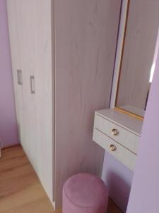 a bedroom with a pink stool and a dresser at Apartman SLADJANA Vrnjacka Banja in Vrnjačka Banja