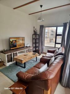 a living room with a leather couch and a table at 1 bedroom Morleen Park apartment in Swakopmund