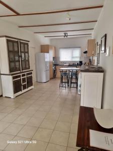 a large kitchen with white appliances and tables and chairs at 1 bedroom Morleen Park apartment in Swakopmund